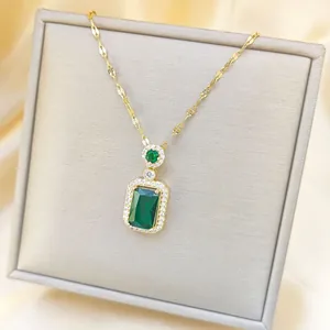 Detail shot of vintage emerald cut green stone necklace with a golden chain and small diamonds
