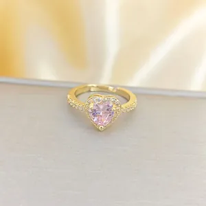 Eleganter goldener Herzring mit rosa Edelstein und Zirkon auf Seidenhintergrund