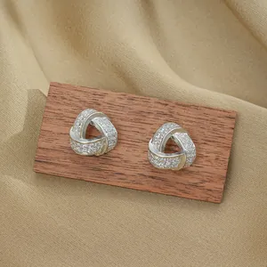 Elegant silver triangle knot earrings with shimmering zircon pavé on silk fabric display