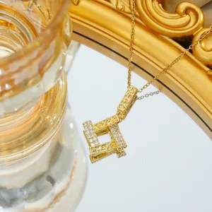 Macro detail of gold geometric square pendant with white zircon and hammer-textured finish