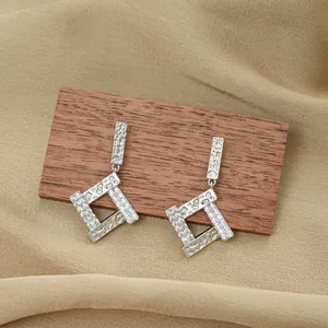 Geometric silver titanium earrings with zircons and textured finish on neutral fabric