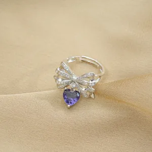 Macro shot of silver bow ring with heart purple gemstone and micro-pave crystals