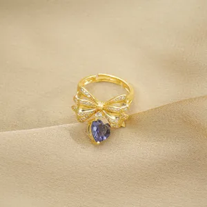 Macro detail of golden bow ring with white zircon pave and purple heart gemstone