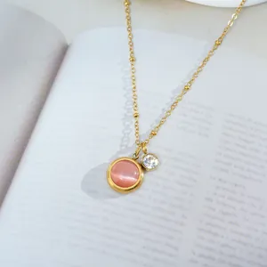 Detail of pink cat-eye stone and white zircon pendant on a gold beaded chain