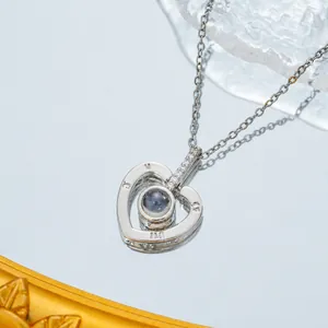 Macro shot of silver heart pendant with projection stone and zircon accents on a chain