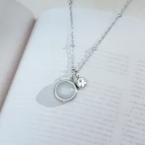 Elegant cat eye stone pendant necklace with silver chain on an open book background