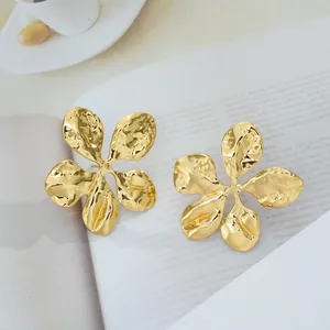 Détail de grandes boucles d'oreilles fleur dorées avec finition martelée sur papier
