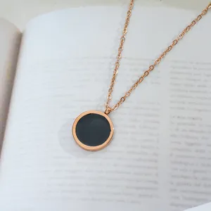 Elegant rose gold titanium steel necklace with black round pendant on an open book