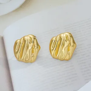 Gros plan sur boucles d'oreilles dorées en acier au design abstrait de lave texturée