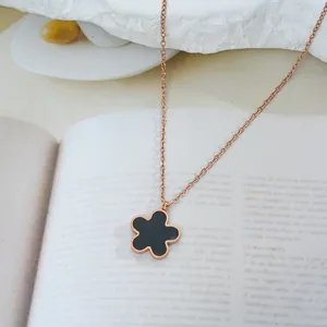 Detailed macro view of rose gold titanium necklace with a black enamel five-petal flower