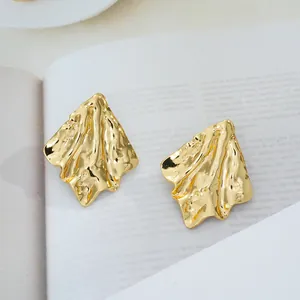 Détails macro des boucles d'oreilles papillon dorées avec surface métallique froissée
