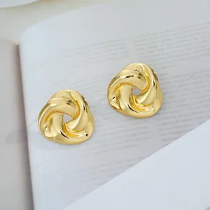 Vue détaillée des boucles d'oreilles triangulaires torsadées dorées sur fond de magazine