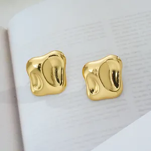 Détail rapproché de boucles d'oreilles dorées de forme organique avec finition polie brillante
