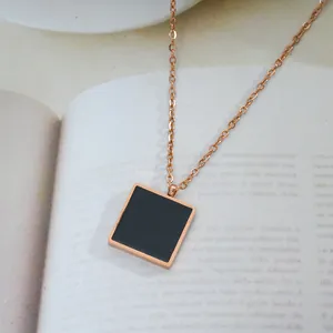 Close-up of rose gold square pendant necklace with black enamel inlay on magazine