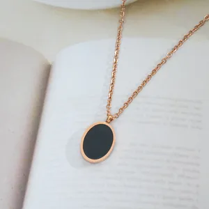 Detail of rose gold oval pendant with black enamel on a book background