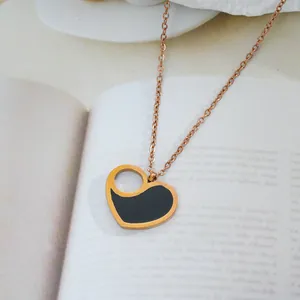 Close-up of heart-shaped black enamel pendant necklace on rose gold steel chain