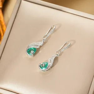 Elegant peacock drop earrings with green teardrop stones in a luxury jewelry box