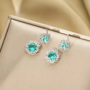 Détail de boucles d'oreilles argentées avec pierres émeraudes et cristaux colorés