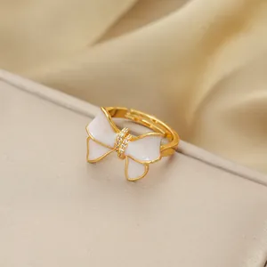 Golden titanium steel open ring featuring white enamel bow and micro-set cubic zirconia