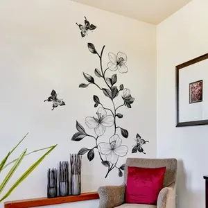 Minimalist black line floral wall sticker with butterflies above a grey leopard sofa