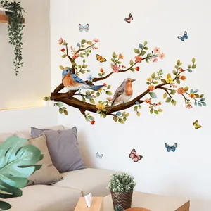 Detail van de vogel- en bloemenmuursticker in een moderne woonkamer boven de grijze bank
