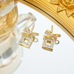 Élégantes boucles d'oreilles nœud doré avec zircons carrés sur une base réfléchissante