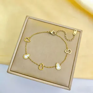 Macro des pendentifs gourde dorés avec incrustations de nacre sur une chaîne fine