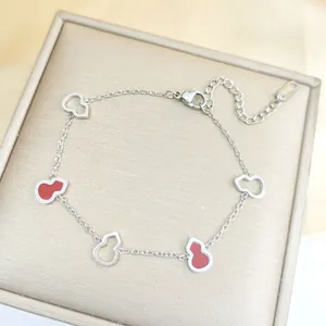 Détail du bracelet en acier inoxydable avec breloques calebasse rouges et fermoir homard