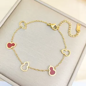 Gros plan du bracelet calebasse plaqué or avec émail rouge et fermoir mousqueton