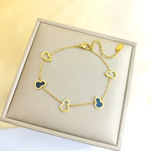 Détail du bracelet en acier titane doré avec des pendentifs gourde noirs et ajourés