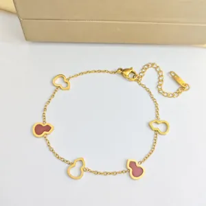 Détail du bracelet en acier inoxydable doré avec des gourdes en émail rouge