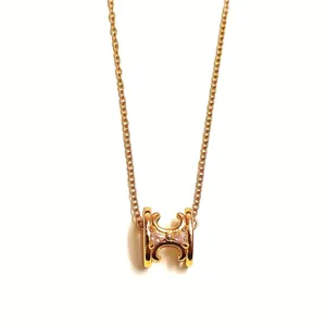 Detailed view of the hollow Triomphe logo pendant on a gold-plated link necklace