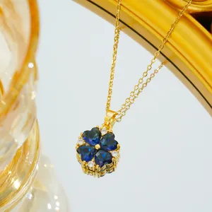 Close-up of golden clover necklace with blue heart-shaped gems and zircon accents