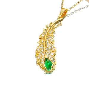 Gold feather necklace with white crystals and a green water-drop stone on white background