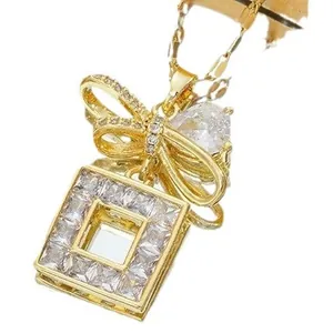 Collier en acier titane doré avec pendentif nœud en zircon sur fond blanc pur