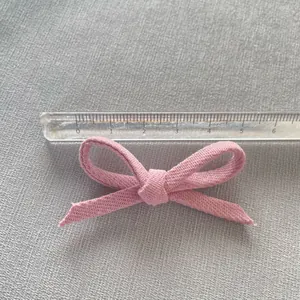 Detailed view of a 6cm pink fabric bow with cotton texture measured by a scale