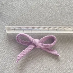 Detail showing a 5.5cm wide purple fabric bow accessory measured with a transparent ruler