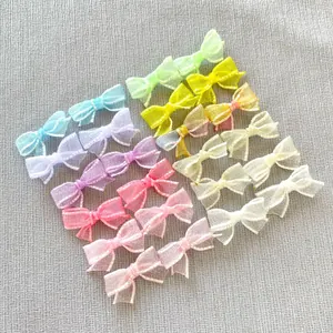 Flat lay of colorful DIY mesh bow accessories in pastel colors on grey texture