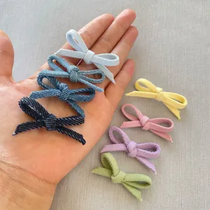 Close-up of handmade fabric bow accessories in various colors held in hand for scale