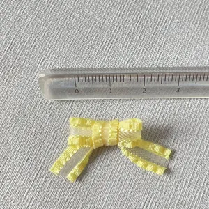Vue macro montrant la taille du mini nœud en organza jaune pour bricolage DIY