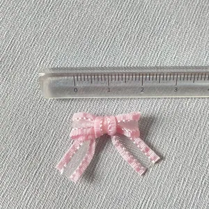 Vue détaillée d'un petit nœud en satin rose de 3 cm avec texture tissée sur lin