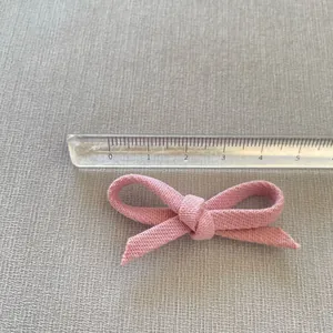 Pink handmade fabric bow hair accessory measuring 5cm in width with textured plain weave