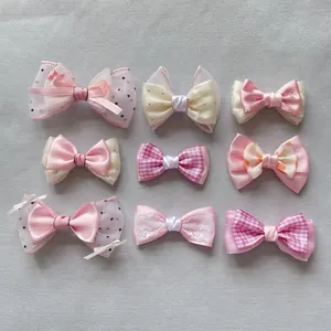 Flat lay of nine handmade plaid mesh bow hair clips in pink and cream tones