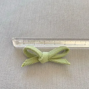Close-up of a handmade grass green fabric bow accessory showing detailed woven texture