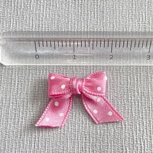 Pink ribbon bow with white polka dots showing 2.5cm size detail on a metric ruler