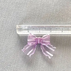 Dettaglio di un mini fiocco in organza viola da 3cm con righello per le dimensioni