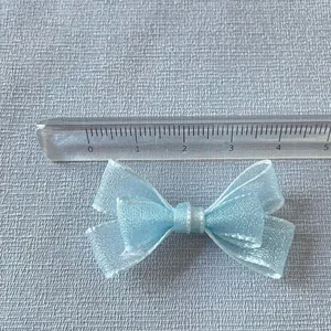 Close-up of a 5cm light blue shimmer silk ribbon bow for crafts and doll clothes