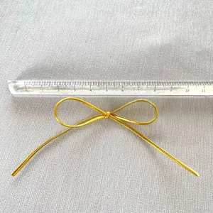 Detailansicht einer 7,5cm goldenen PU-Leder-Schleife für DIY-Deko mit einem Maßstab