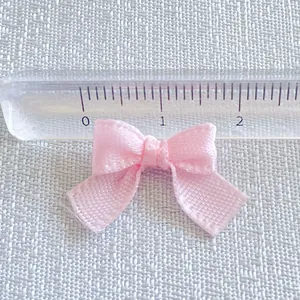 Close-up of a 2cm pink macaron satin ribbon bow with fine mesh texture and ruler detail