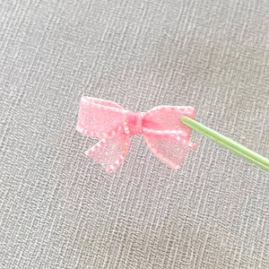 Detail of a pink mesh ribbon bow with fine stitched edges for DIY craft and doll clothing